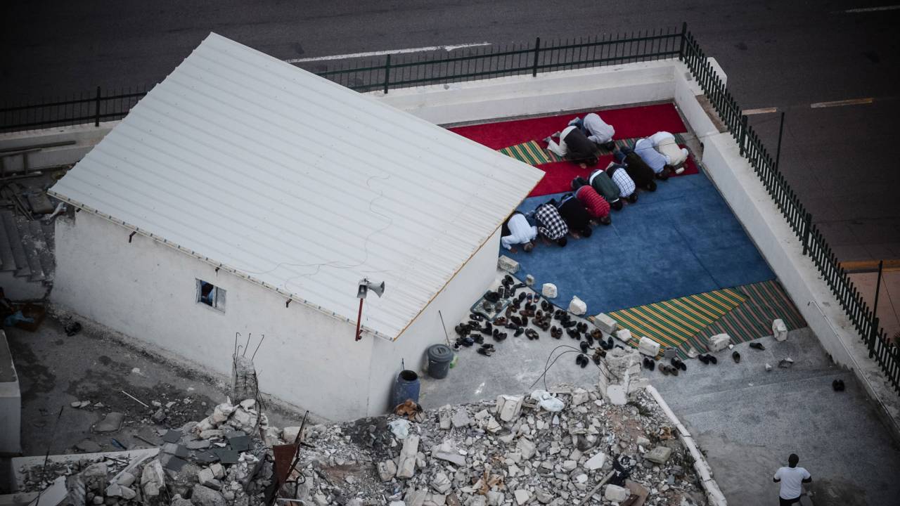 Men praying beside the ruins of their bombed mosque in Tripoli.